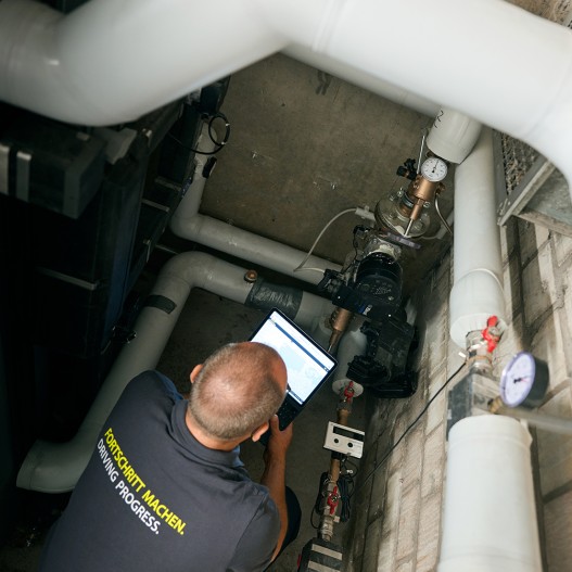 Technikraum, Draufsicht auf Techniker bei der digitalen Erfassung von Zirkulationspumpen-Betriebsdaten